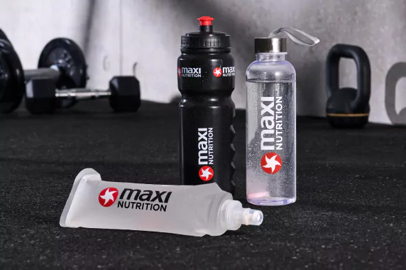 maxinutrition-trinkflaschen-weiss-transparent-und-schwarz-vor-fitnessstudio-hintergrund