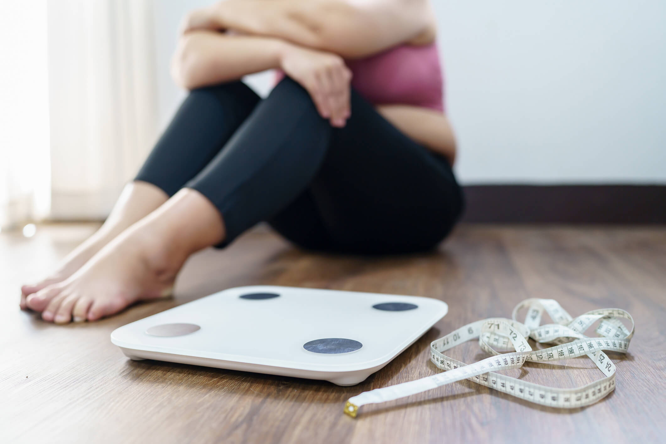 maxinutrition-Bauchfett-verlieren-Strategien-für-Gesundheit-und-Wohlbefinden-Frau-sitzt-neben-Waage