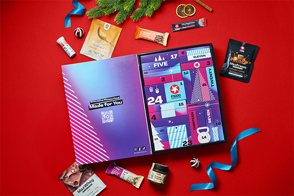 maxinutrition fitness food adventskalender geöffnet und inhalte daneben auf rotem hintergrund
