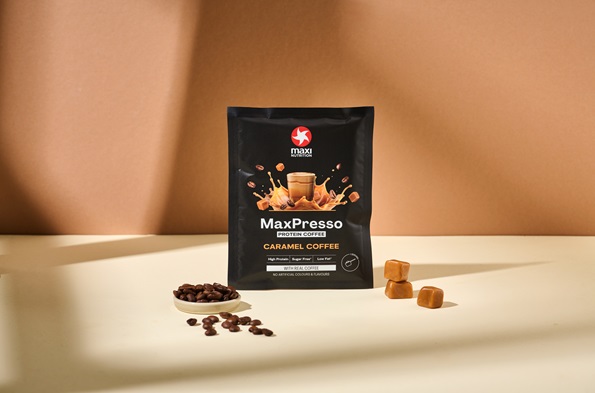 maxinutrition_MaxPresso_Caramel_Coffee_Sachet_stehend_vor_brauner_wand_mit_zutaten