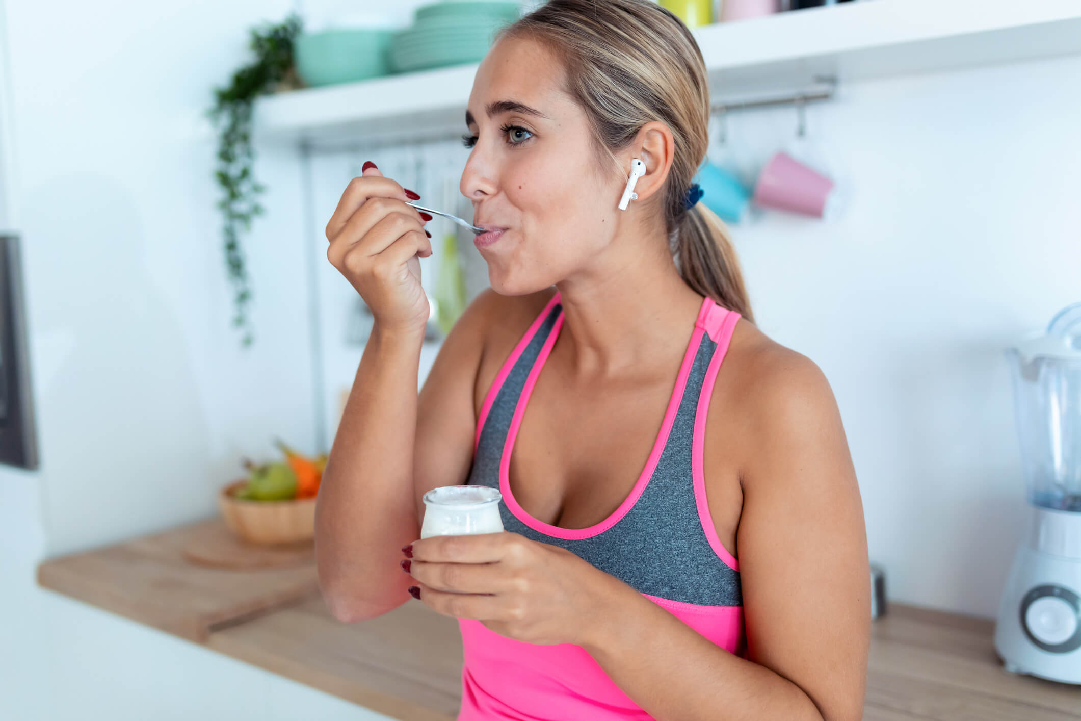 maxinutrition muskeln definieren - frau isst joghurt und hört musik 